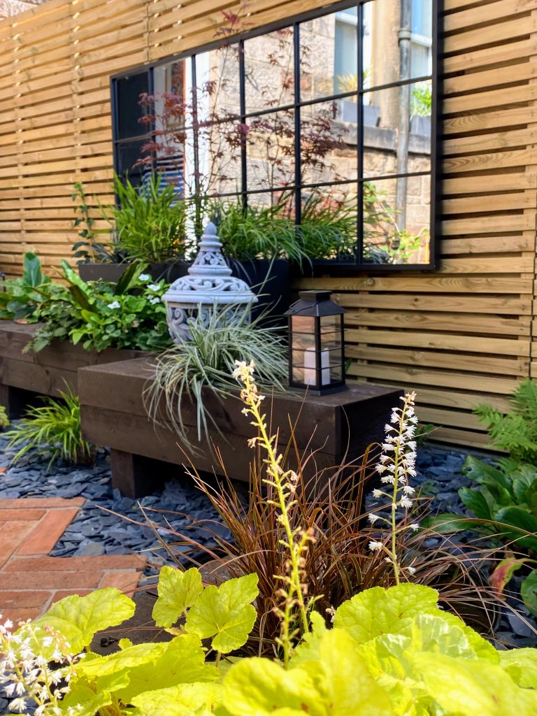 Elegant outdoor mirror with lush green accents.