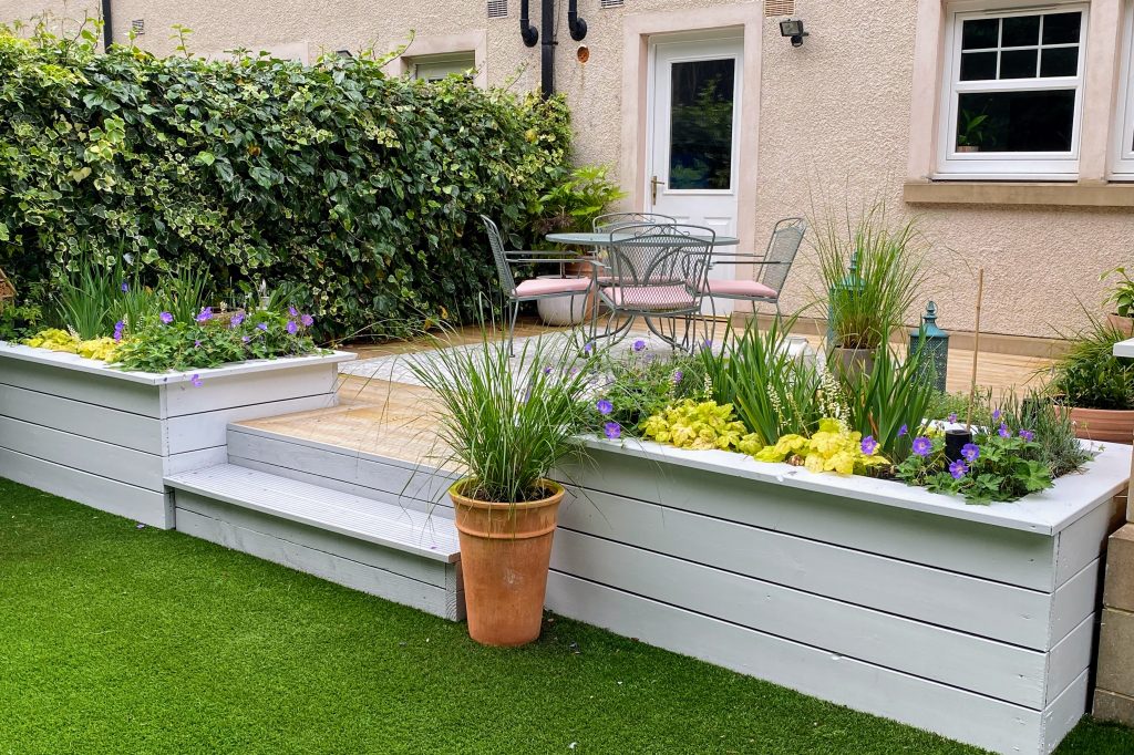 Elevated garden in Edinburgh with tiered planting beds, vibrant flowers, and functional seating.