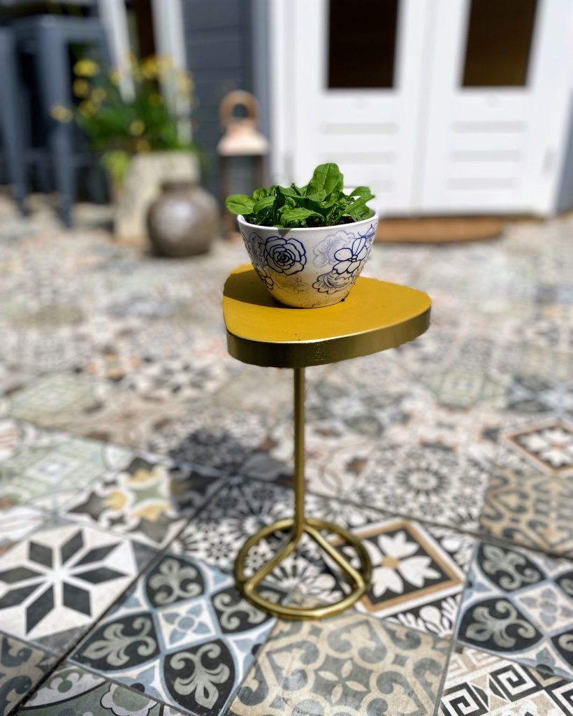 A golden accent table adds elegance to this tiled garden patio, designed for small Edinburgh spaces