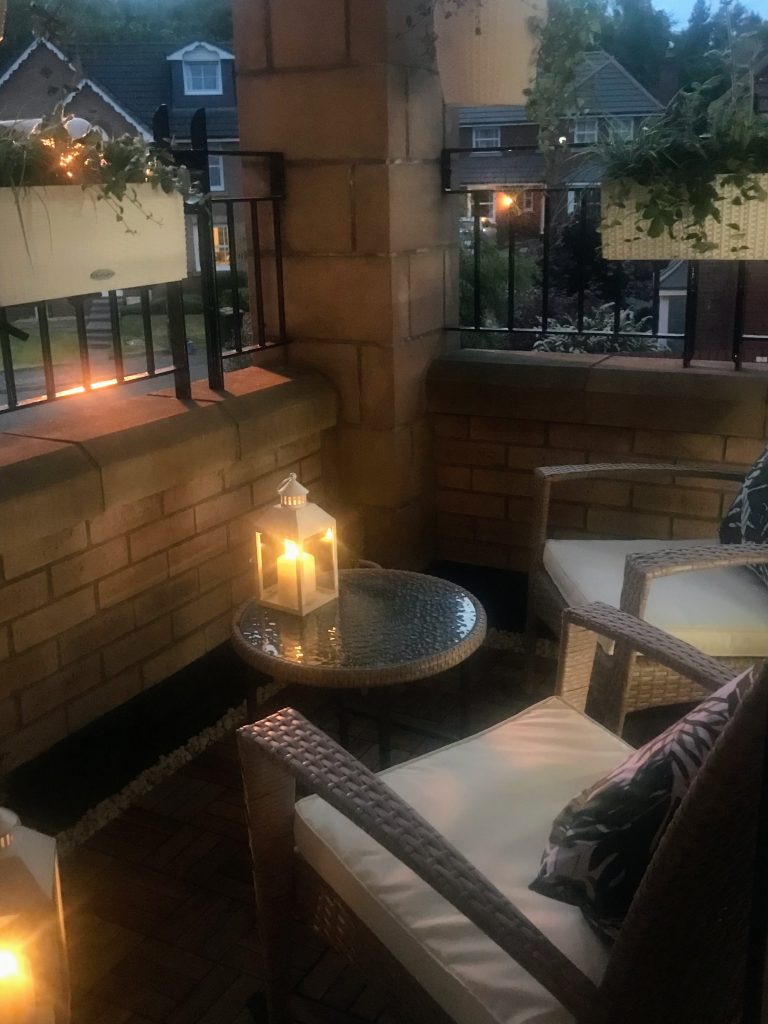 Cosey balcony with night lighting and lush greenery.