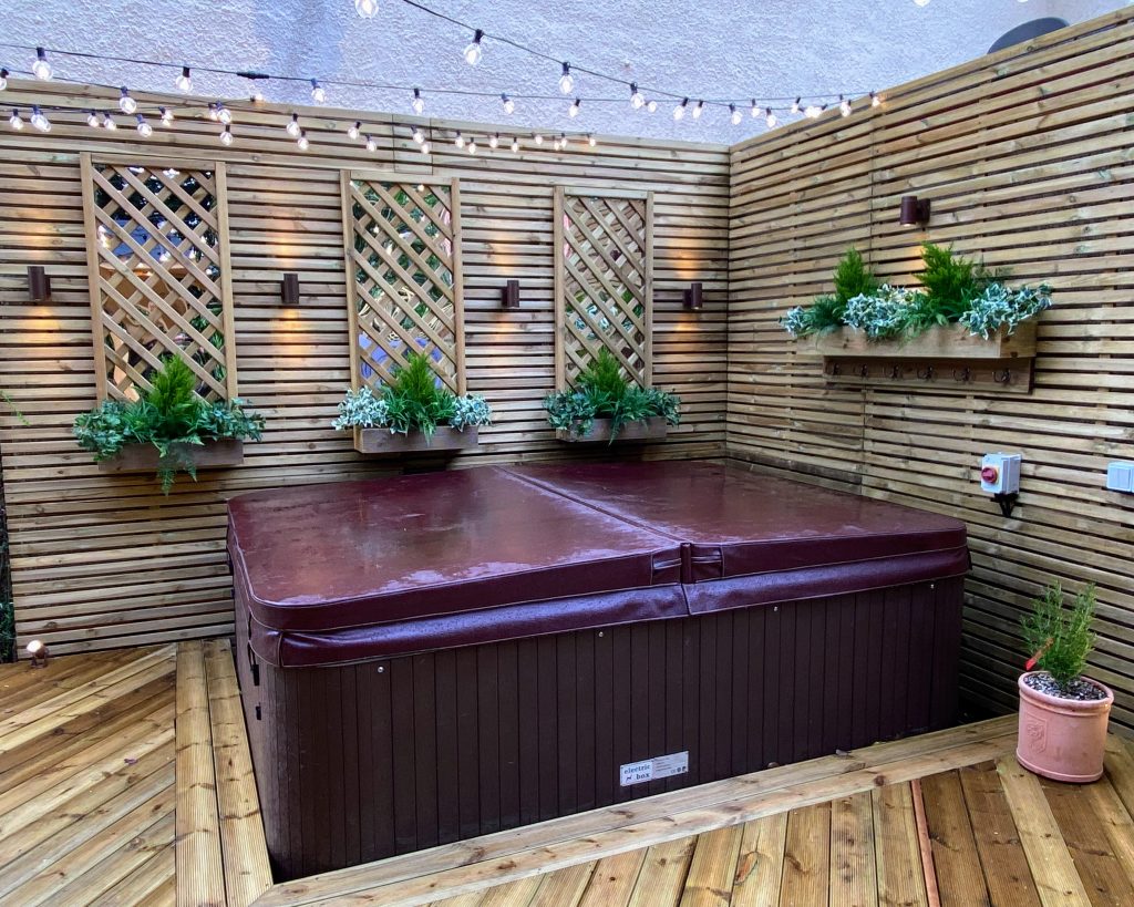 Relaxing outdoor hot tub with lattice wall design and planters.