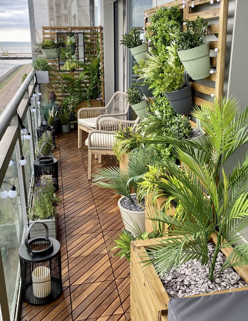 Edinburgh balcony transformed with wooden decking, lush green planters, and cosey seating.