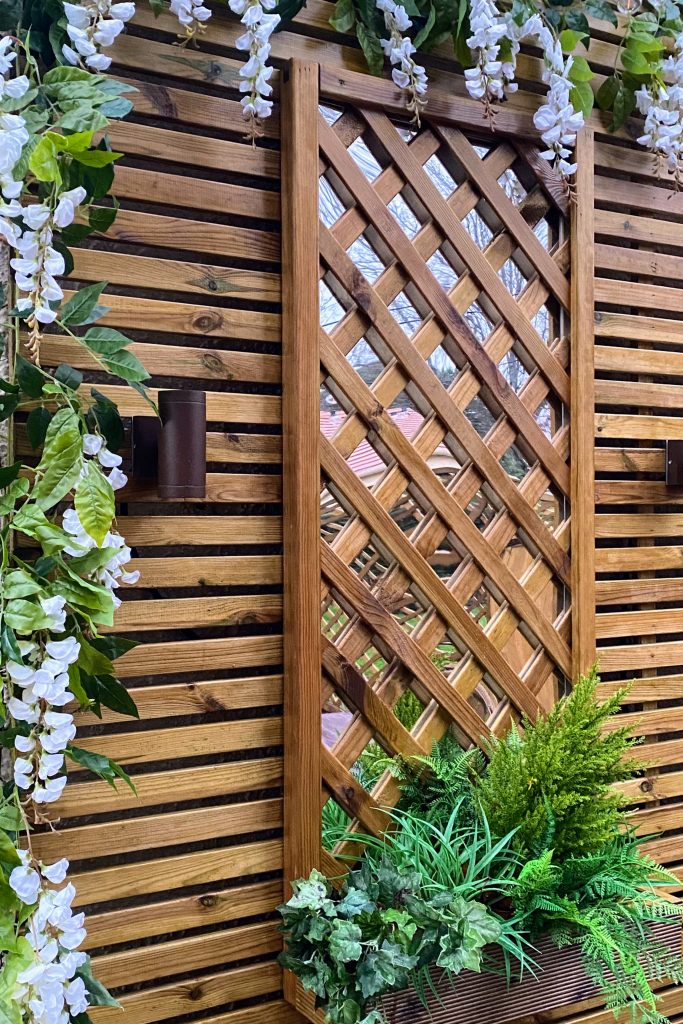 Vertical trellis with cascading faux flowers and plants for garden décor.