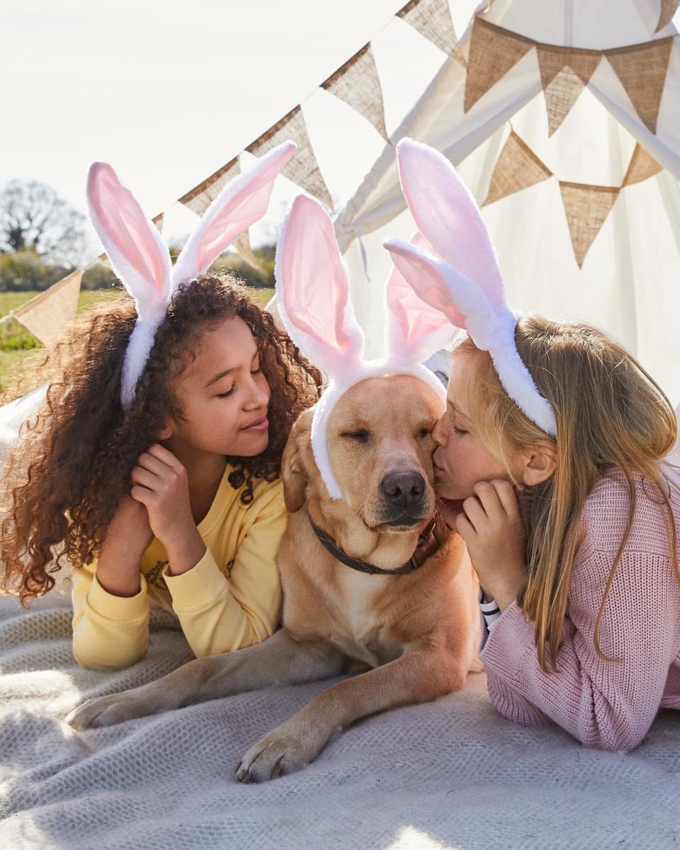 Two children and a Labrador wearing pink bunny ears during an outdoor Easter photoshoot styled by Angela Moffat, Stylist, Edinburgh, Scotland.