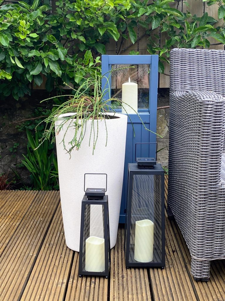 Elegant white planter with candle lanterns for a cosey patio atmosphere.