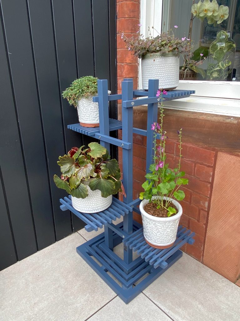 Stylish blue tiered plant stand for compact outdoor plant displays.